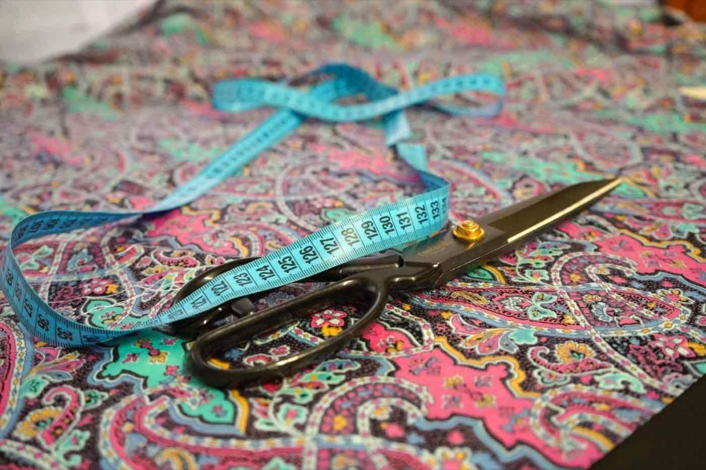 Paisley-Stoff mit Stoffschere und Maßband auf dem Zuschneidetisch